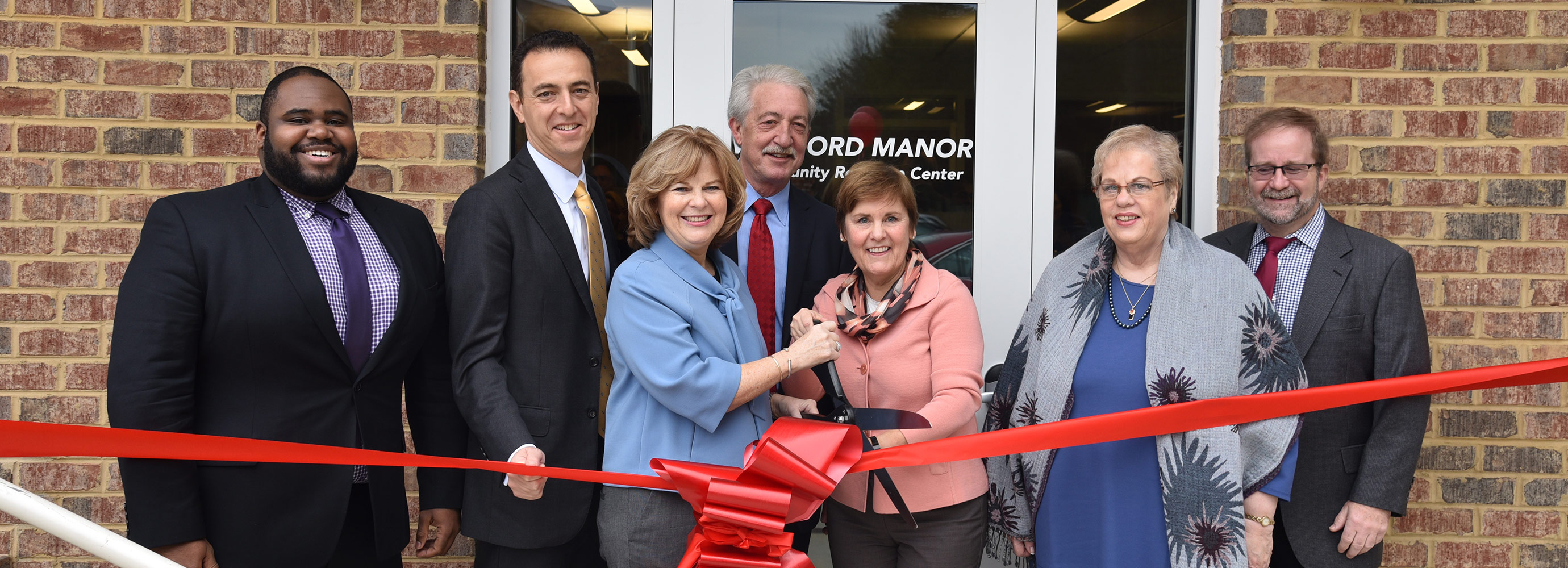 Happy team members cutting the ribbon at Wexford Manor