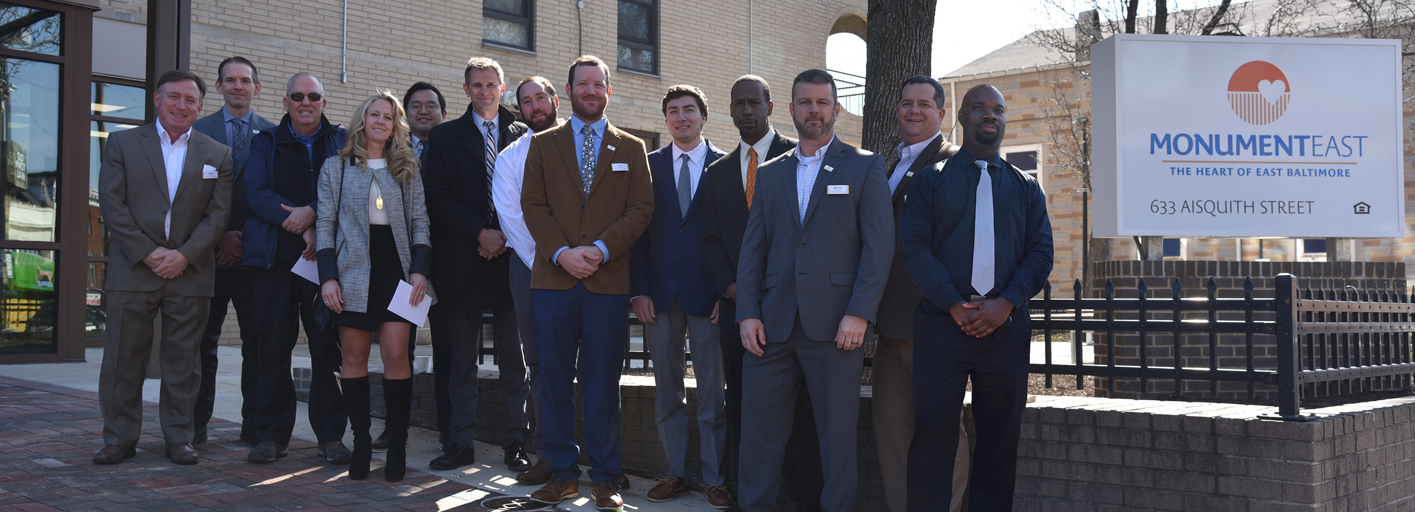 Harkins group photo in front of building sign for ribbon cutting event