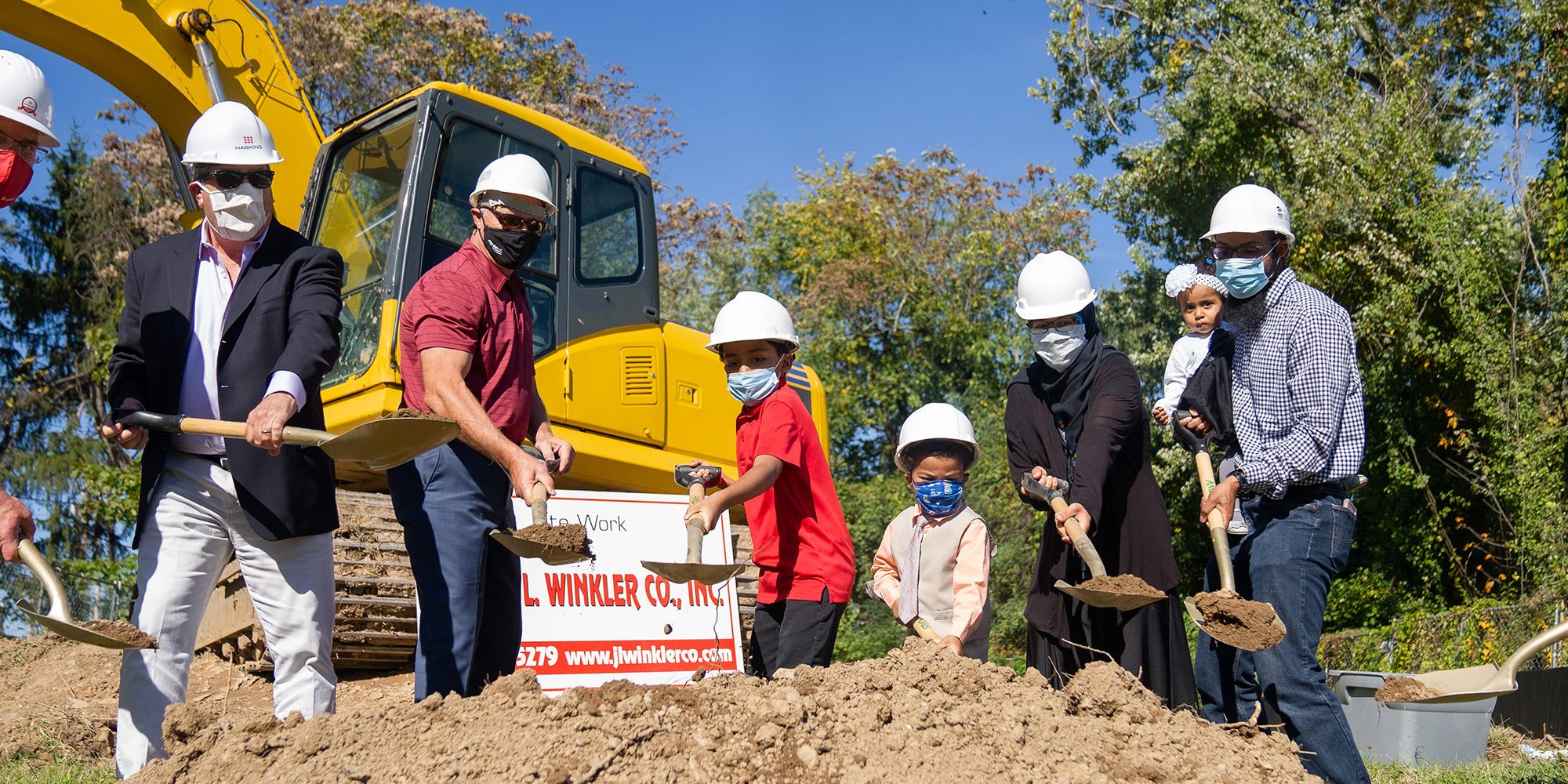 Harkins Builders shoveling dirt into a pile with the recipients of the house.