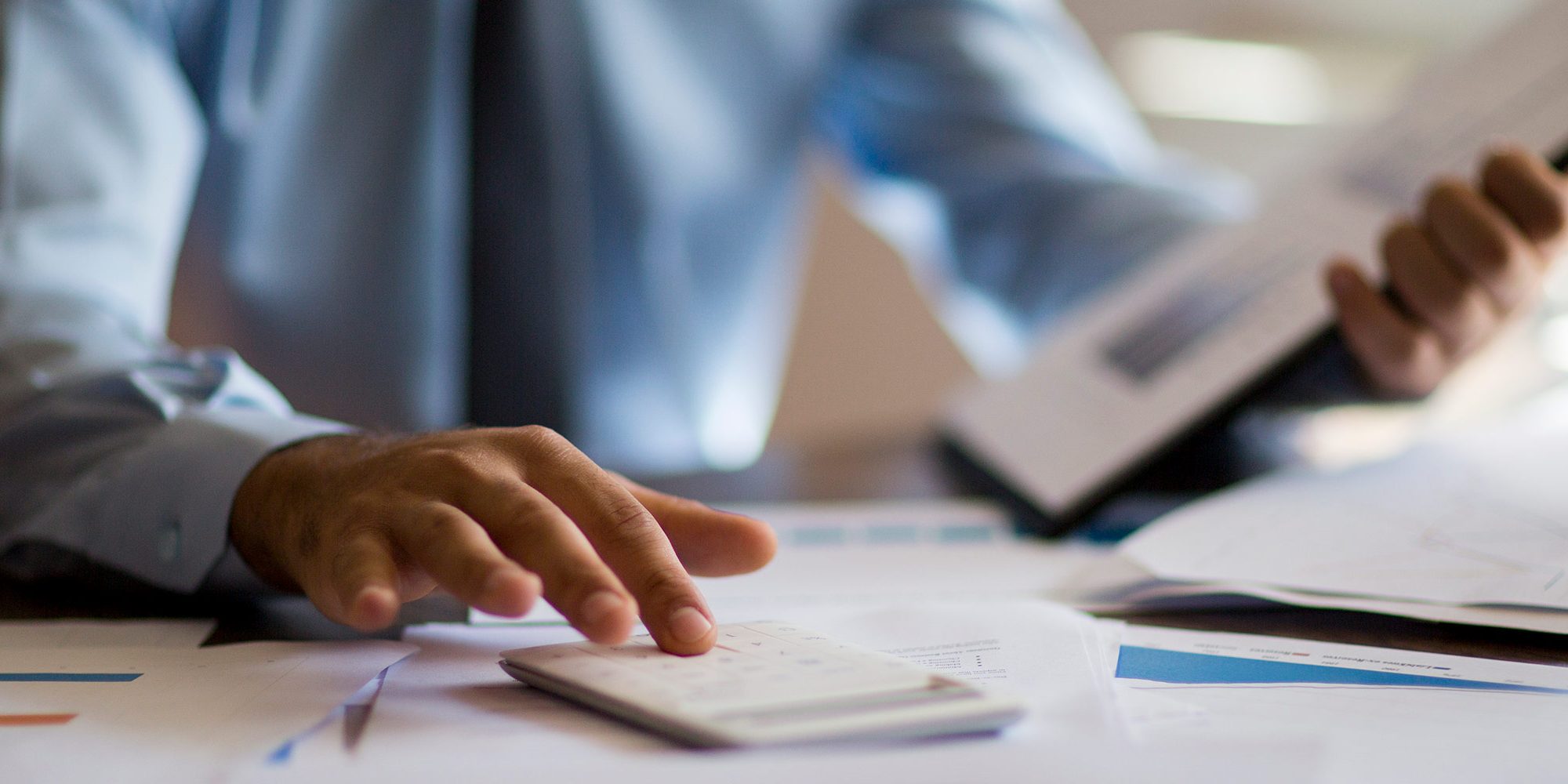 Accountant looking at files and typing on calculator